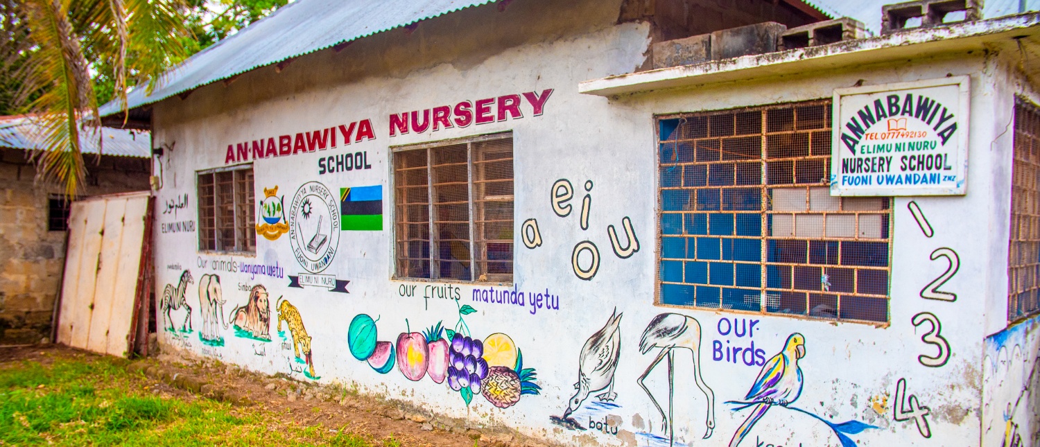 A vibrant nursery school building in Zanzibar, adorned with colorful educational murals of animals, fruits, and numbers.