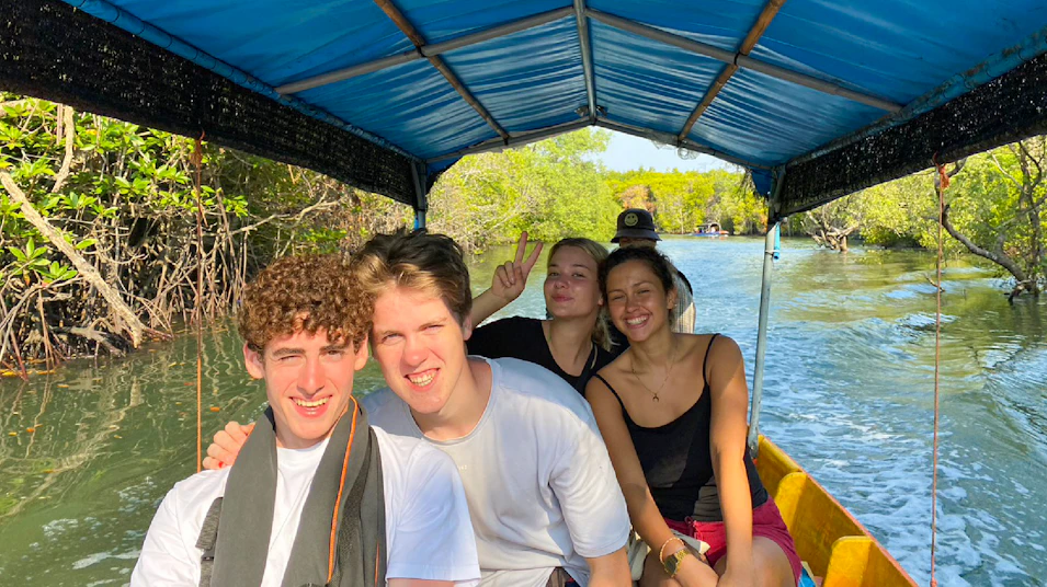 Smiling young friends enjoy a scenic longtail boat trip through Thailand's mangrove forests.