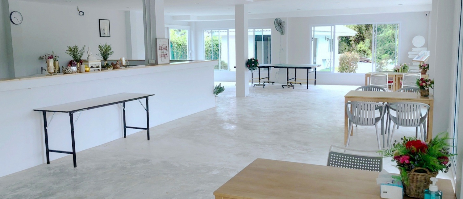 Bright, modern common area with tables and chairs, a welcoming space for volunteers in Thailand.