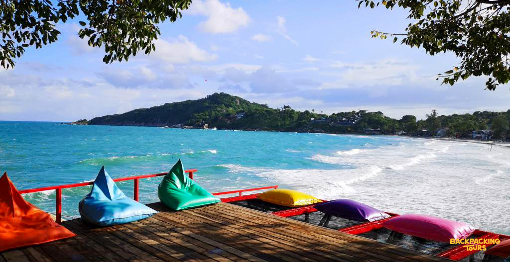 A vibrant deck with colorful beanbags offers stunning views of the turquoise ocean on Koh Phangan.