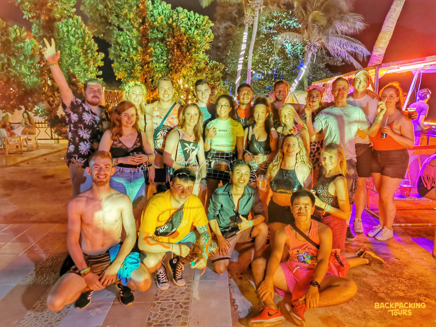 Smiling backpackers gather for a group photo at the famous Full Moon Party on Koh Phangan.