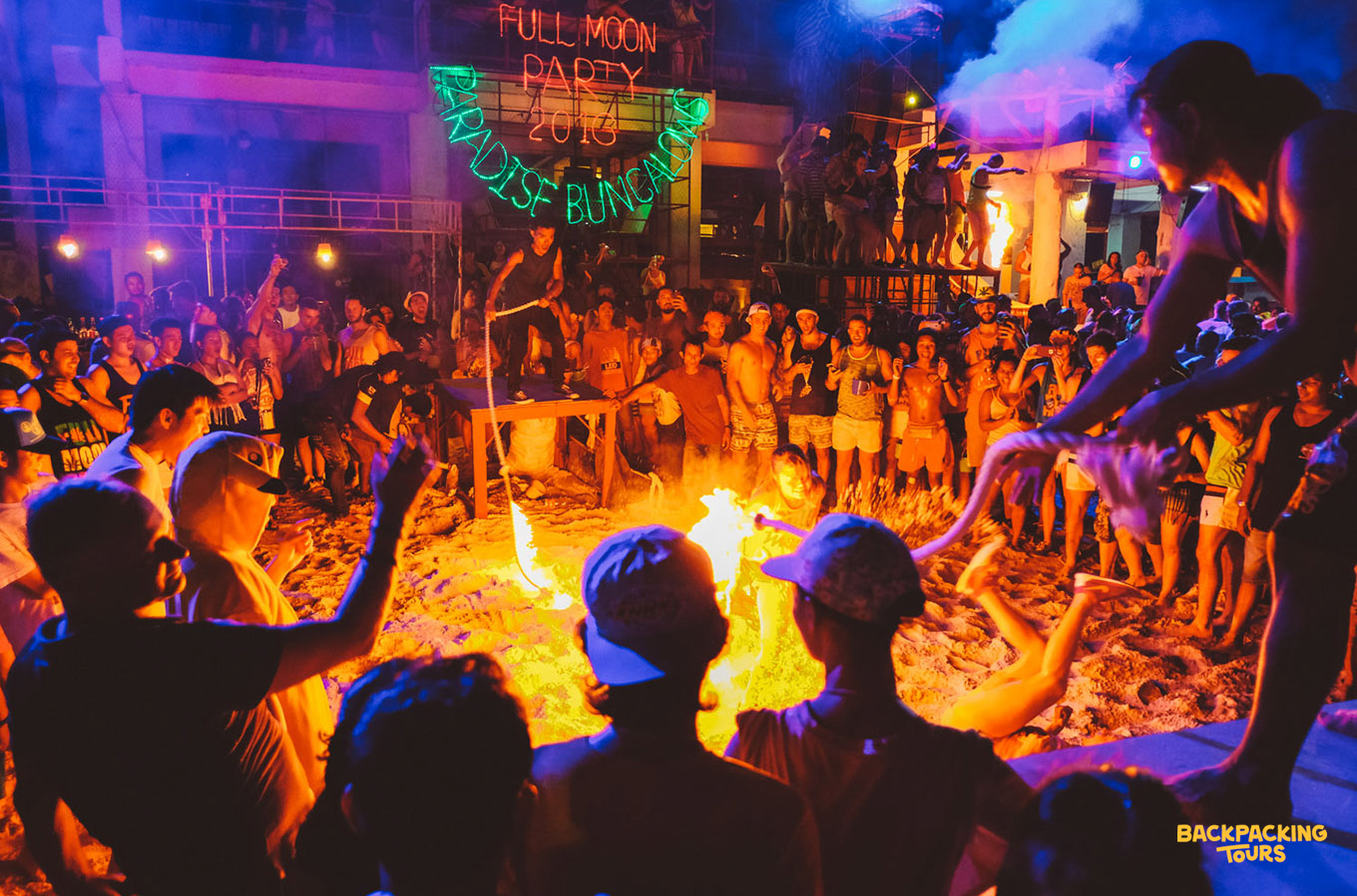 Energetic crowd enjoys the Full Moon Party on Koh Phangan, with a flaming skipping rope in action.