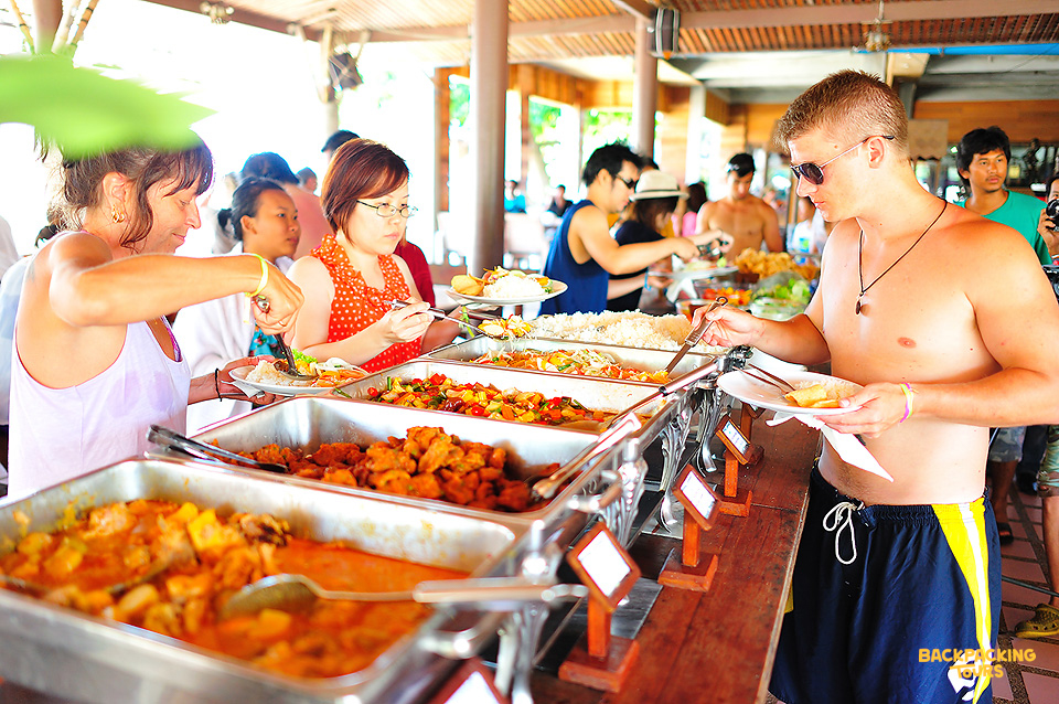 Travelers in swimwear serve themselves from a vibrant buffet spread during their island hopping tour.