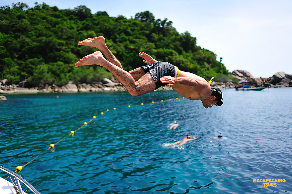 A man dives headfirst into the clear blue waters of Koh Nangyuan for an exciting snorkeling adventure.