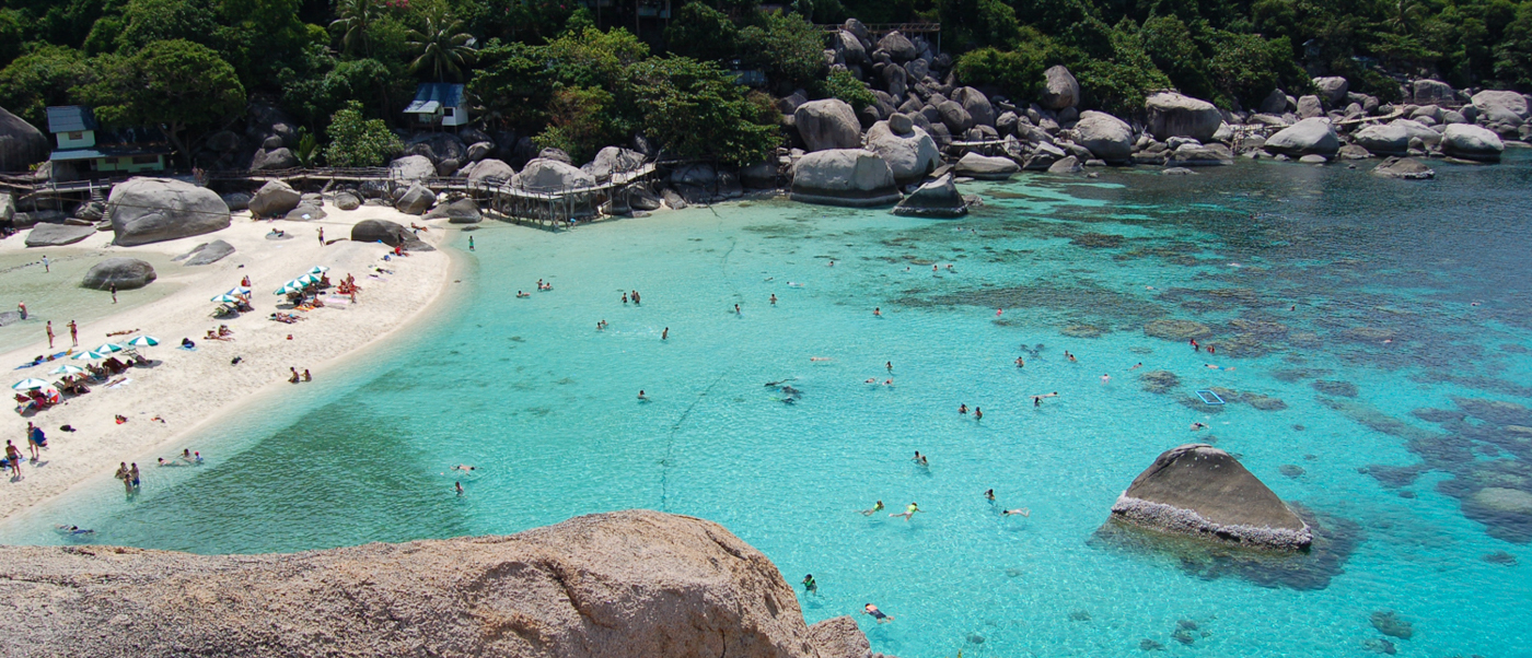 People swim and relax on the white sand beach of Koh Nangyuan with clear turquoise water.