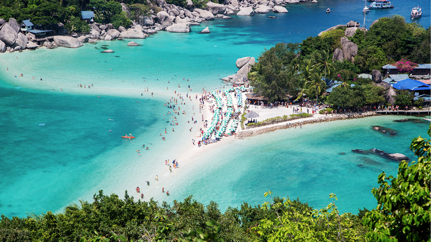 Tourists relaxing on the white sandbar and swimming in the clear blue sea at Koh Nangyuan.