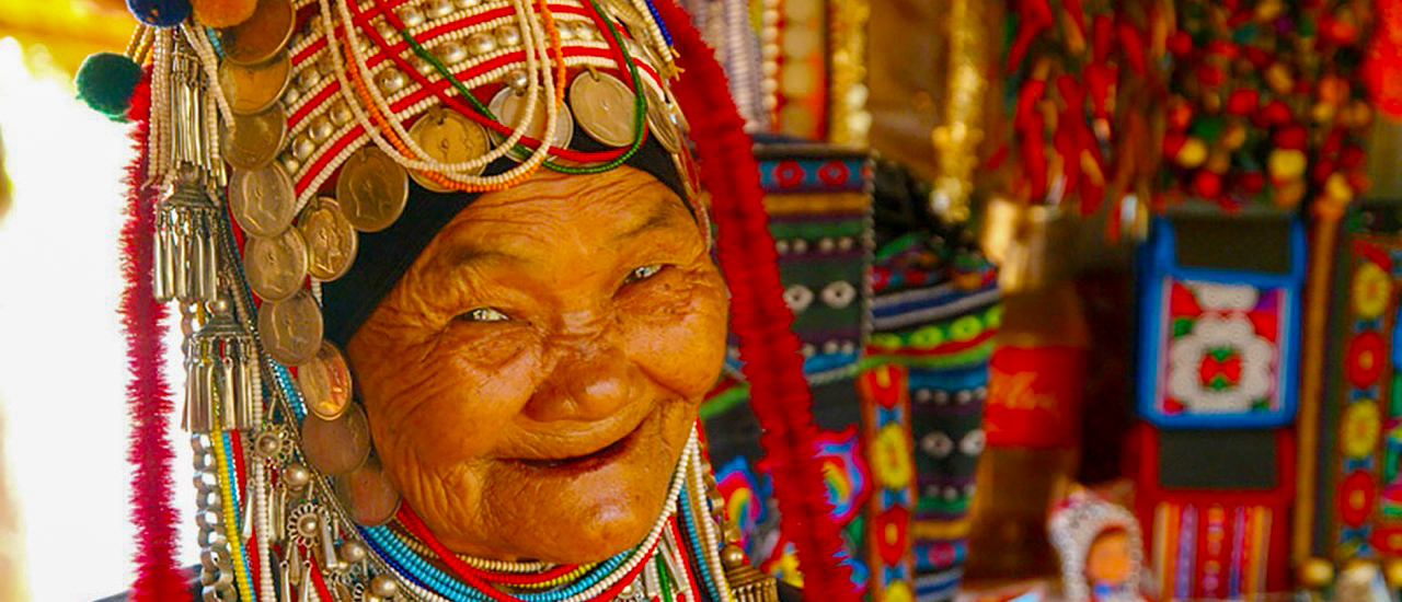 Elderly hill tribe woman smiling in traditional costume with coin headdress in Chiang Mai.