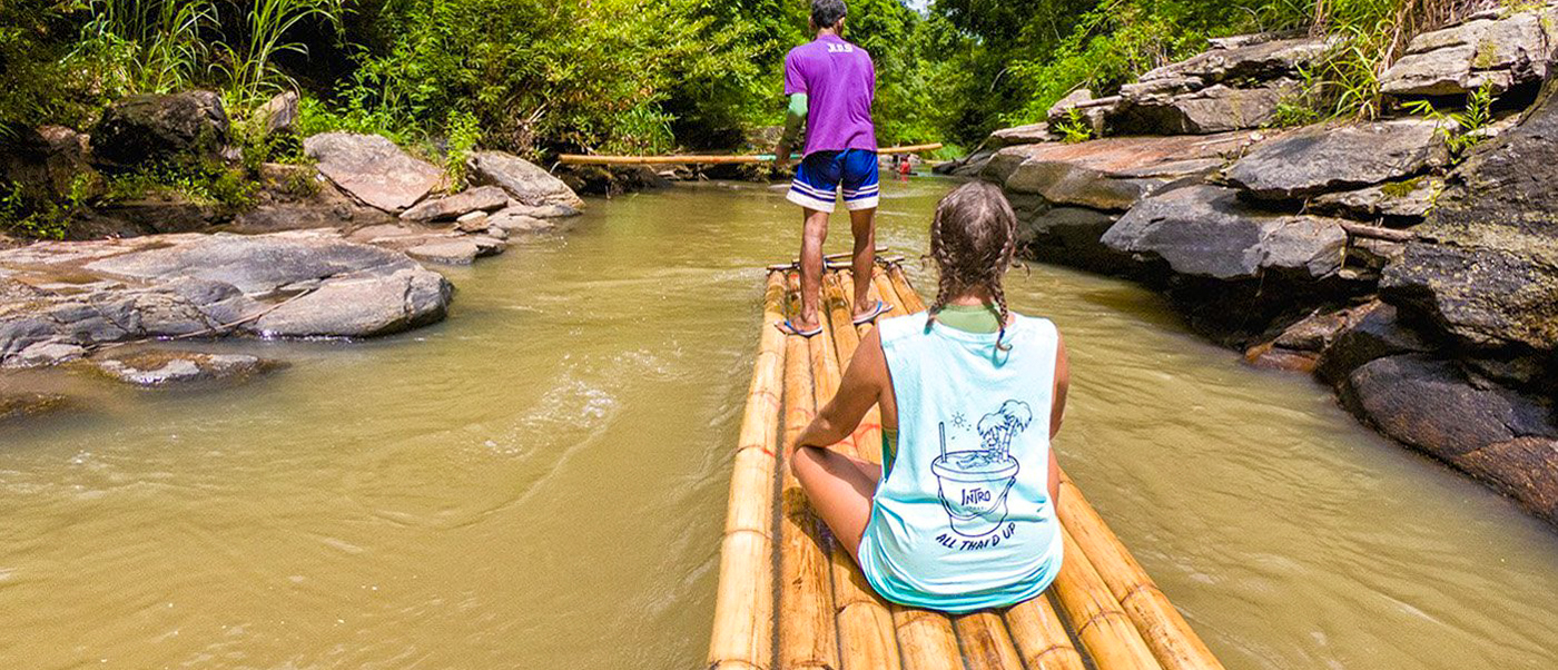 Two people enjoy a peaceful bamboo rafting adventure down a river in Chiang Mai.