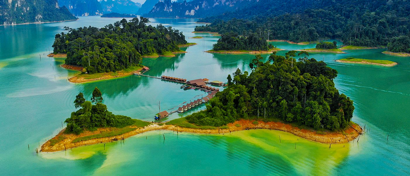 Floating bungalows on a vibrant turquoise lake surrounded by lush jungle islands in Khao Sok National Park.