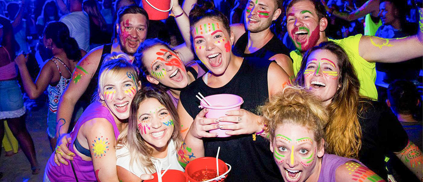 Smiling backpackers with glow paint on their faces enjoying a lively beach party on Koh Phi Phi.