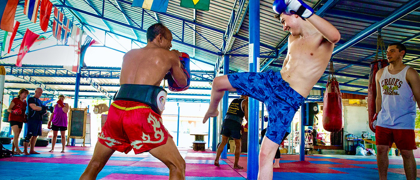A student practices a high kick with an instructor during a Muay Thai class in Koh Phangan, Thailand.