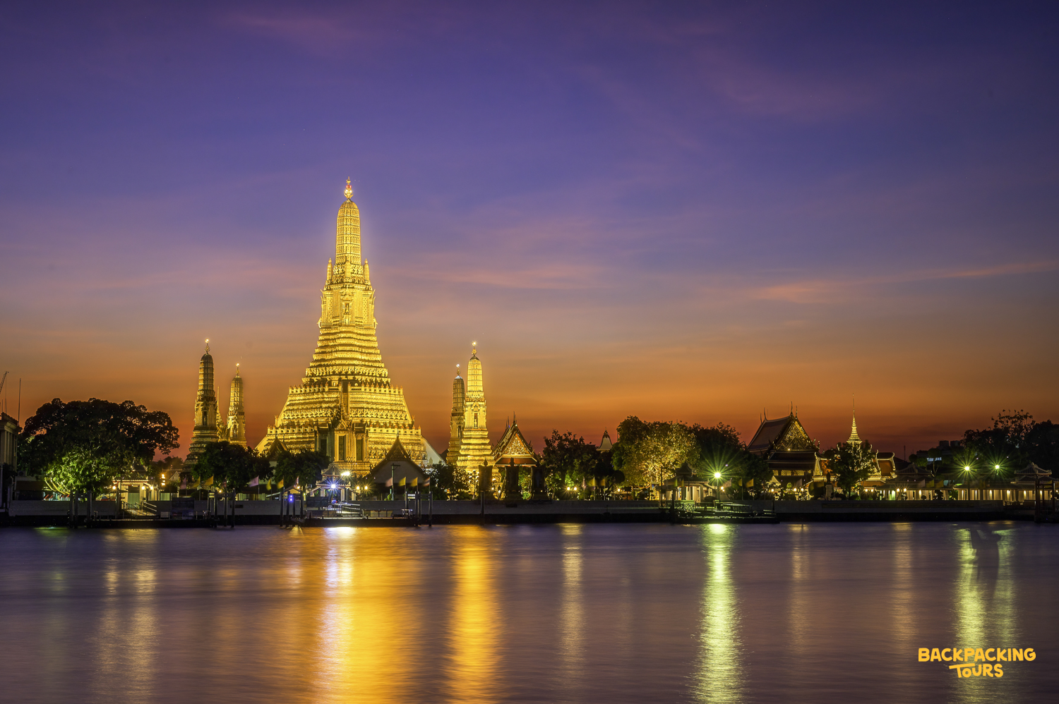 Wat Arun temple in Bangkok glows golden at sunset, reflected beautifully in the Chao Phraya River.