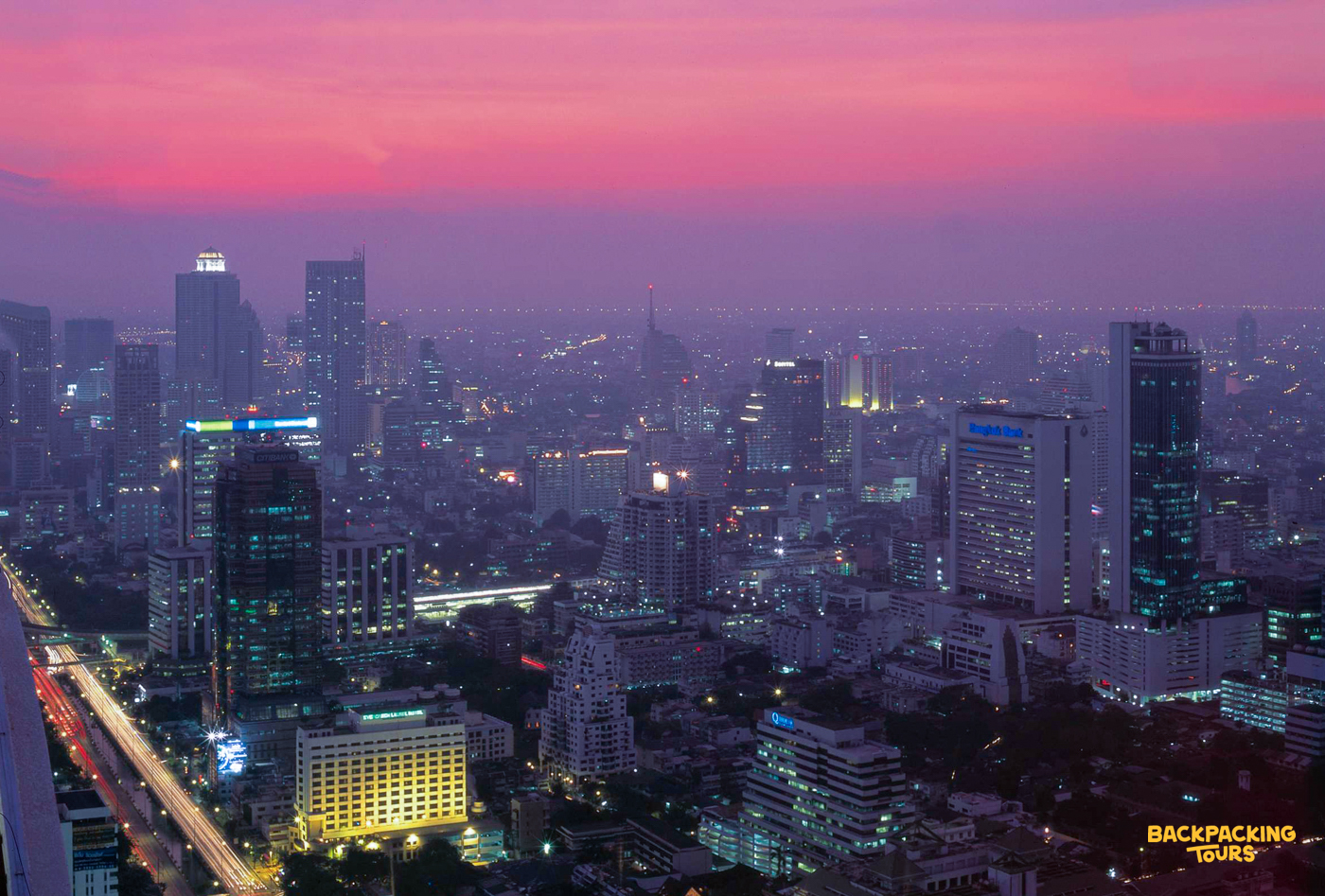 Bangkok city skyline at sunset, with a beautiful pink and purple sky and illuminated skyscrapers.