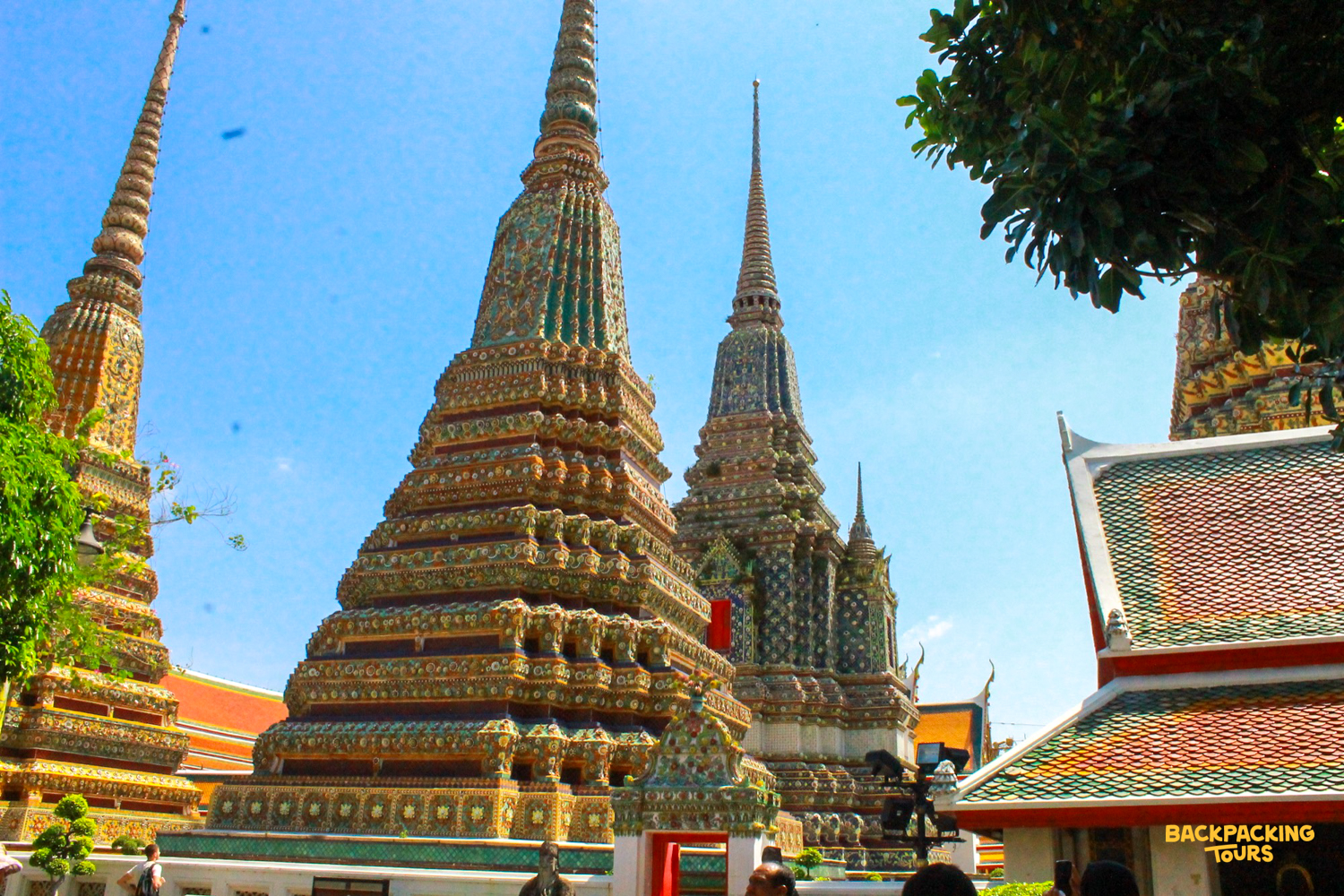 Ornate temple spires with colorful mosaics reaching towards a clear blue sky in Bangkok.