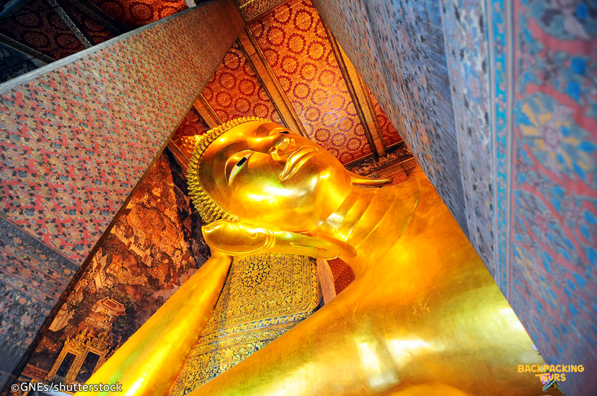 A majestic golden reclining Buddha statue with intricate details inside Wat Pho temple in Bangkok.