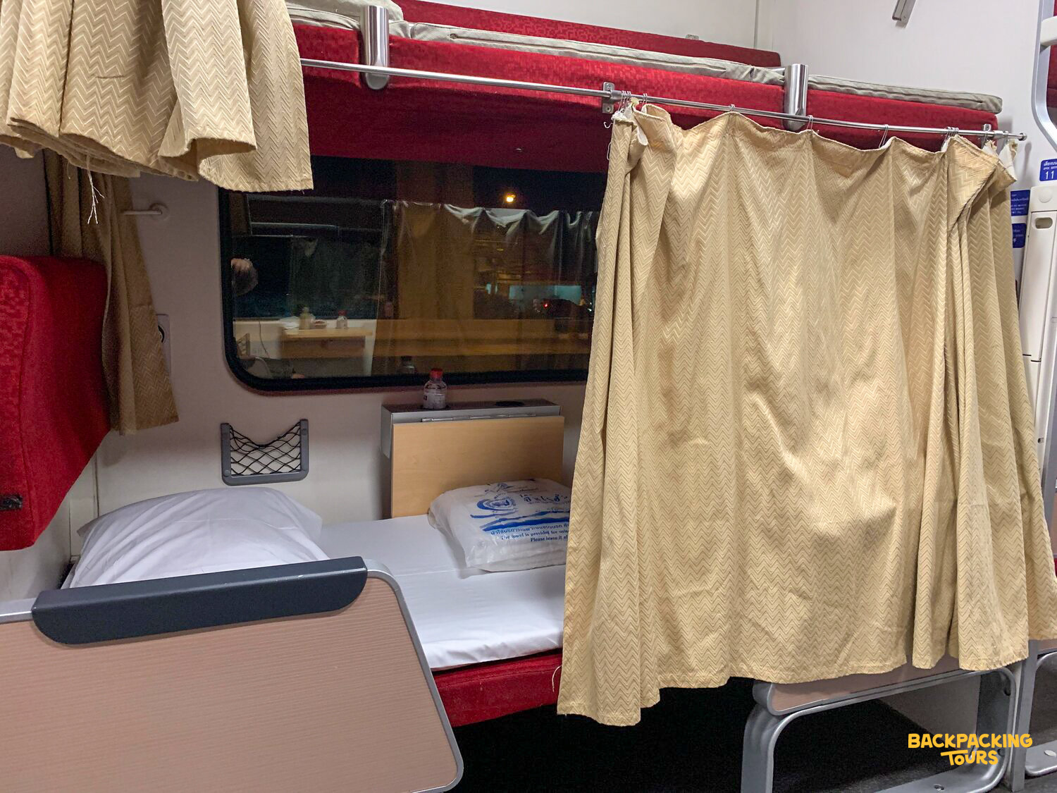 A comfortable sleeping bunk with a privacy curtain on an overnight train in Thailand.