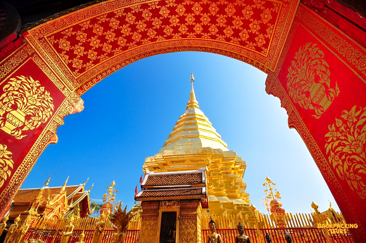 Golden chedi of Wat Phra That Doi Suthep in Chiang Mai, framed by a vibrant red and gold archway.
