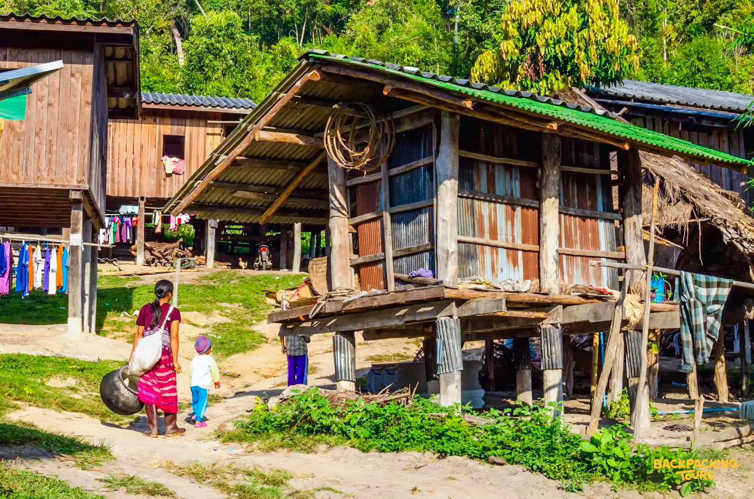 A woman and child walk past traditional wooden houses in a Hmong village near Chiang Mai.