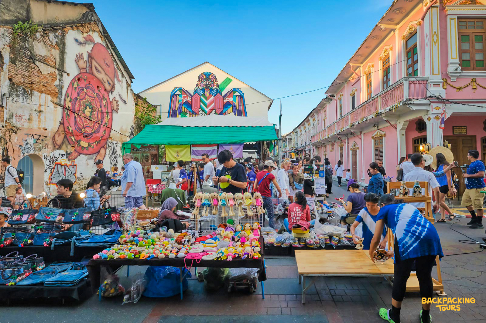 Shoppers browse colorful stalls at a lively street market in Phuket Old Town, Thailand.