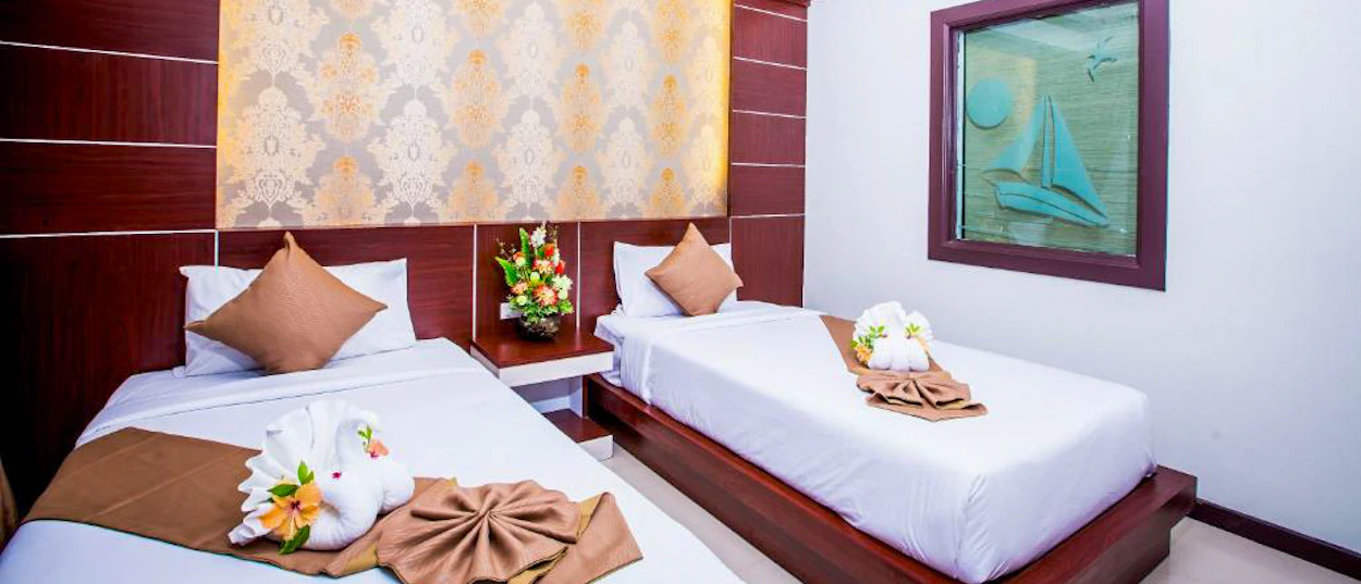 Inviting twin beds with swan towels and fresh flowers in a hotel room on Phi Phi Islands.