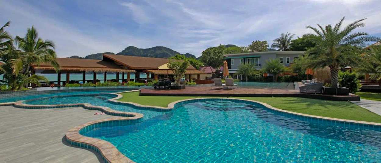 Tropical resort with winding blue swimming pools, palm trees, and a restaurant overlooking the sea on Phi Phi Islands.