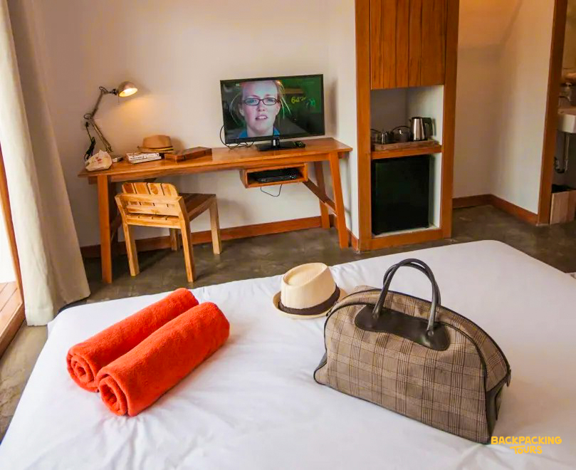 A cozy resort room on Koh Samui with a bed, fresh towels, and a travel bag awaits.