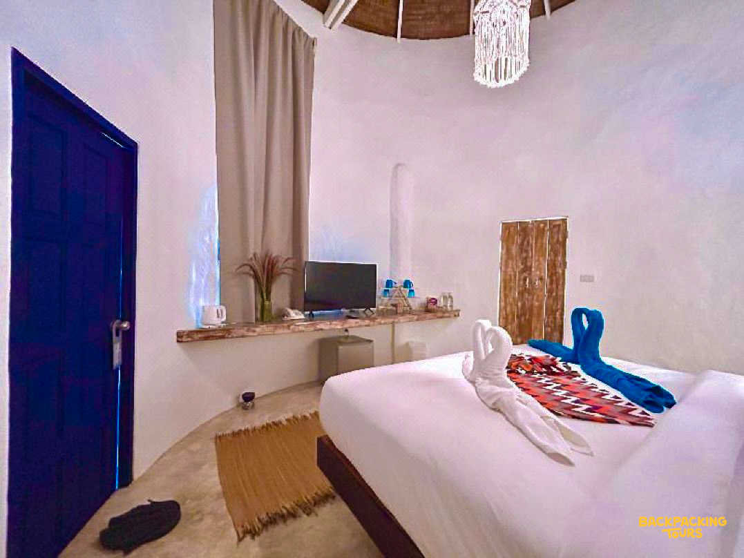 A bright and airy resort bedroom on Koh Phangan with a large bed and swan-folded towels.