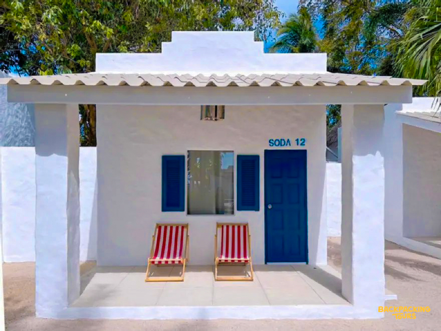 White bungalow with blue door and striped chairs on the porch, a welcoming stay in Koh Phangan.