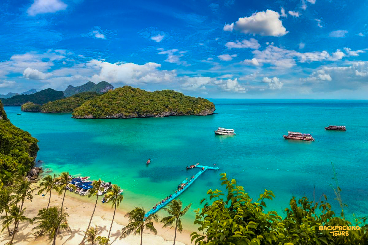 Tropical paradise in Koh Samui with clear turquoise water, a long pier, and lush green islands.