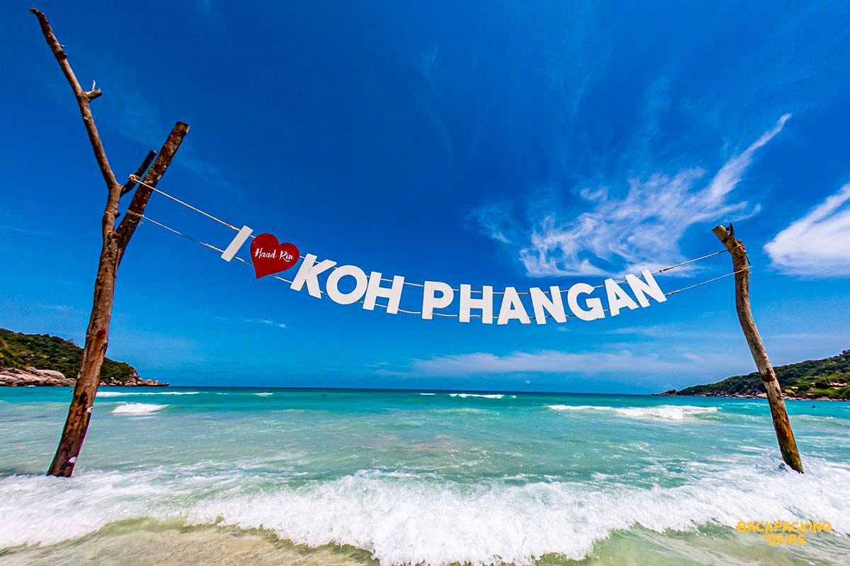 A welcoming 'I love Koh Phangan' sign on a stunning tropical beach with clear blue water.
