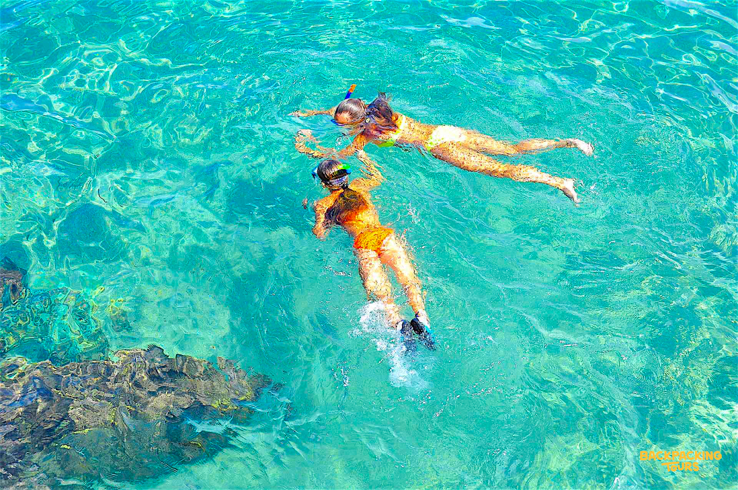 Two snorkelers glide through the crystal-clear turquoise waters of Koh Tao, exploring the vibrant marine life.