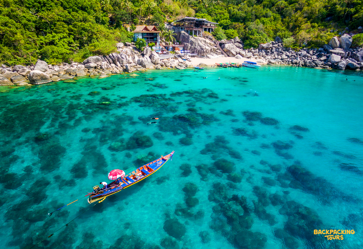Snorkelers enjoy the crystal-clear turquoise waters of Mango Bay, Koh Tao, from a traditional longtail boat.