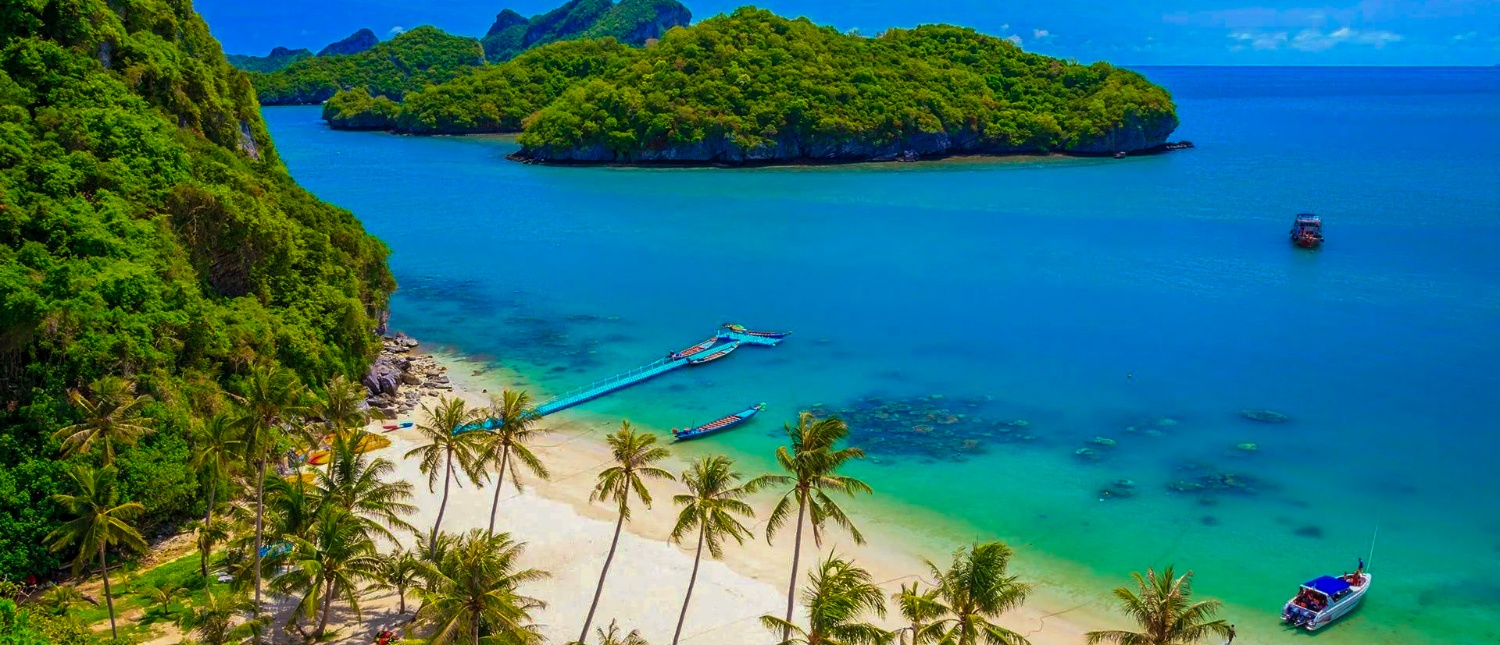 Stunning tropical beach with white sand, palm trees, clear water, and green islands in Koh Samui.