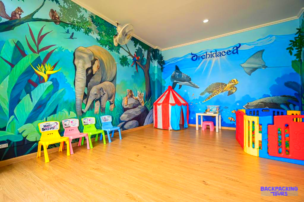 A vibrant children's play area with jungle and underwater murals, a tent, and colorful furniture.