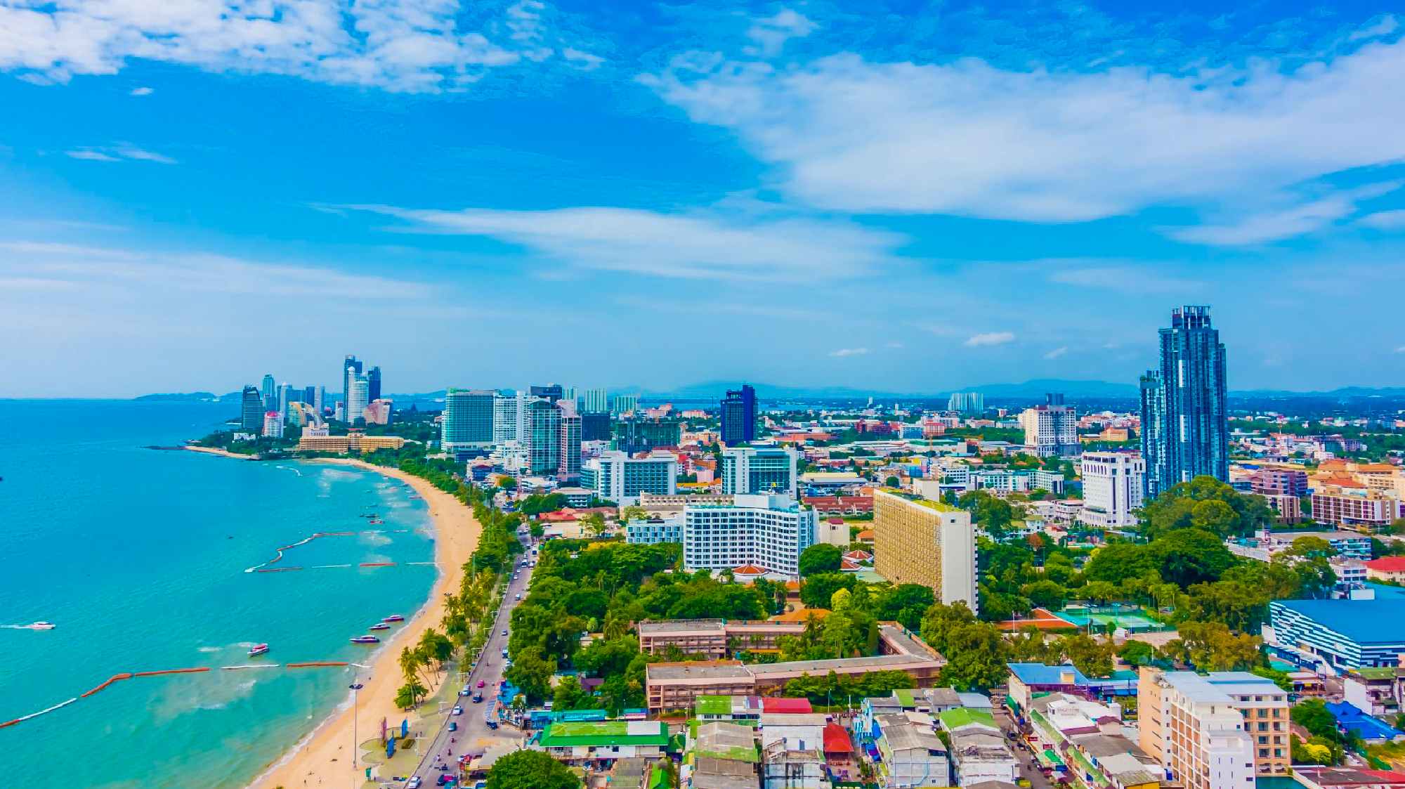 Aerial view of Pattaya, Thailand, showcasing its long beach, turquoise sea, and modern city skyline.