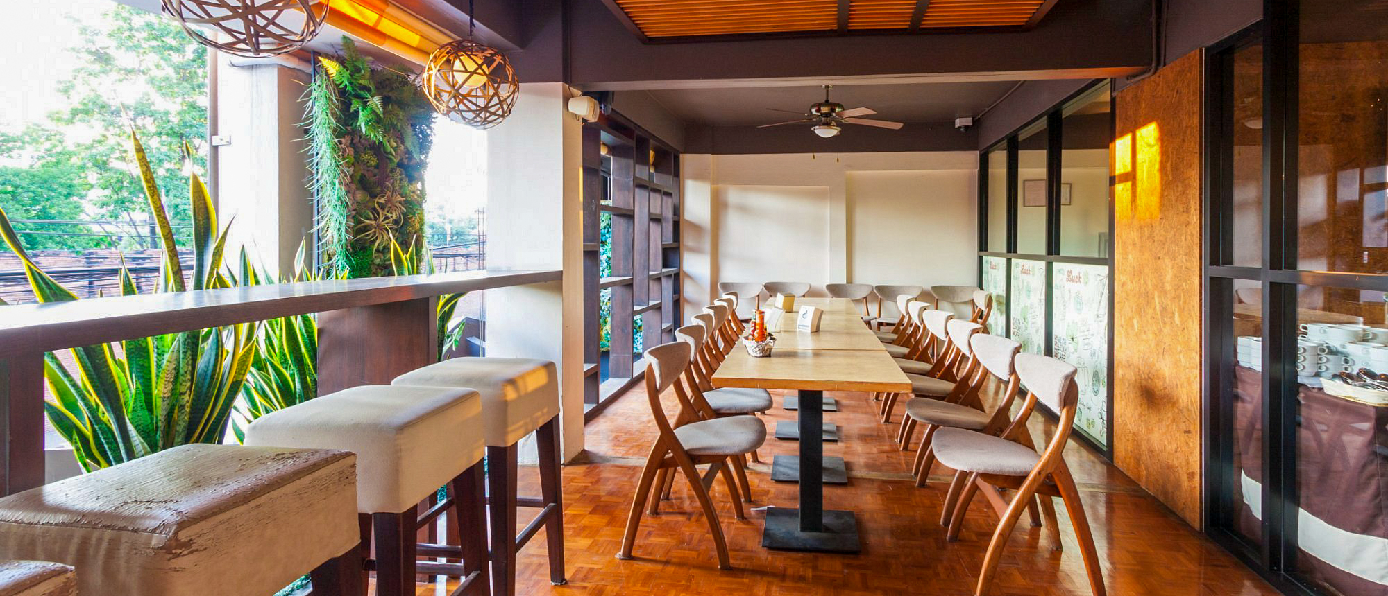 A modern and inviting cafe interior in Chiang Mai, featuring a long dining table and bar.