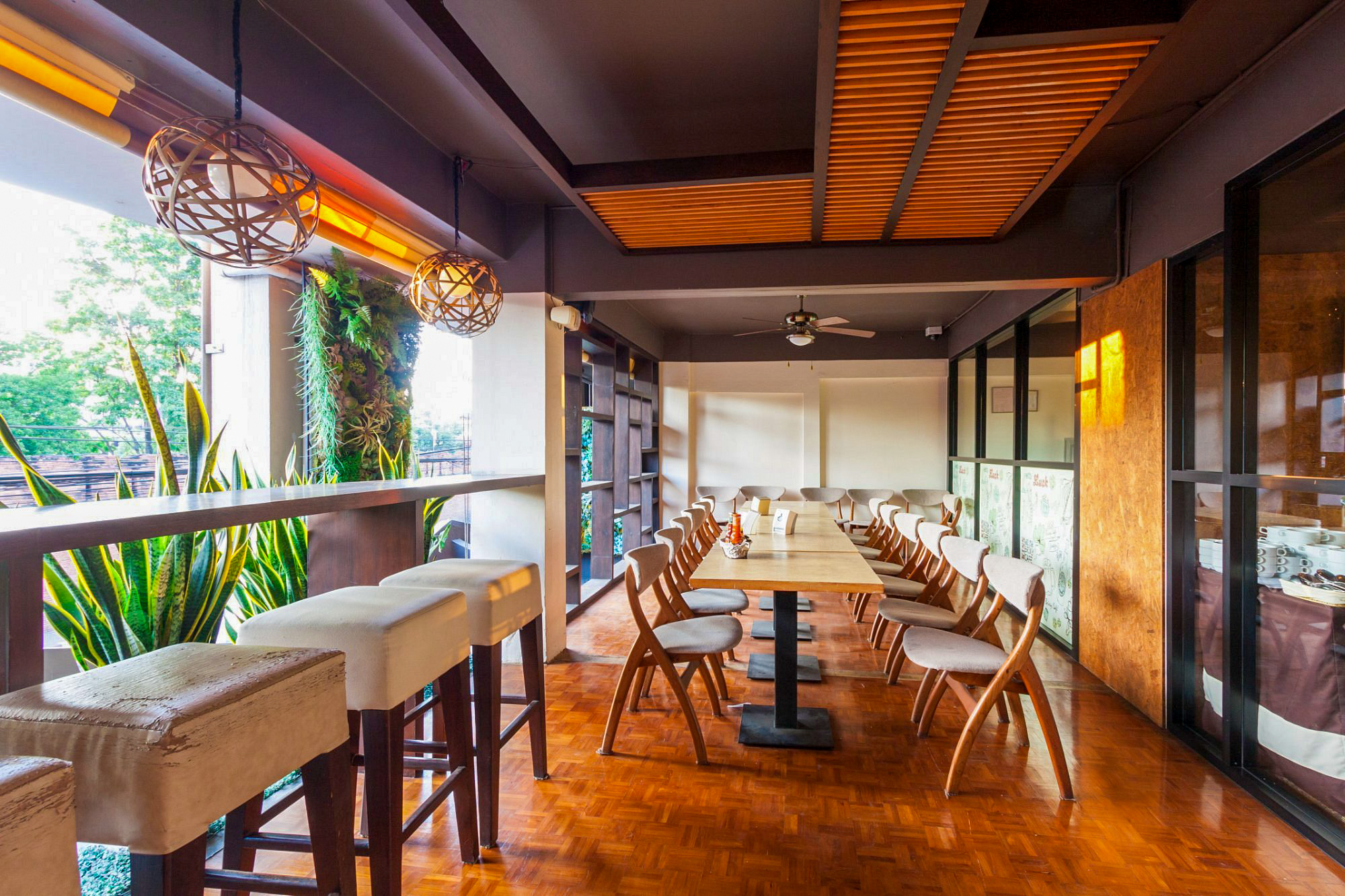 An inviting hotel restaurant in Chiang Mai featuring a long dining table and a charming outdoor patio.