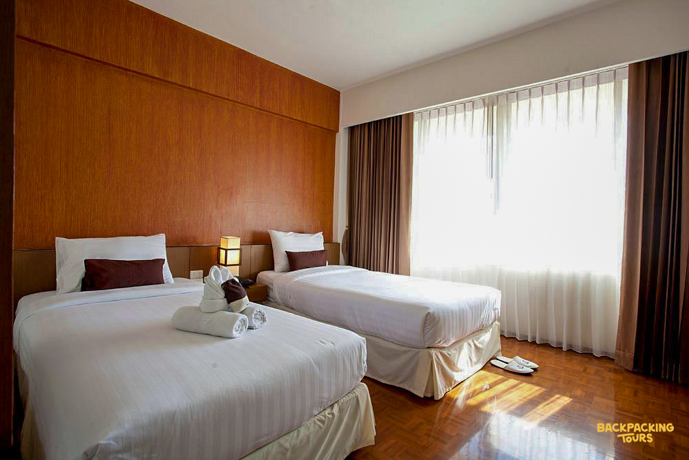 A welcoming hotel room in Chiang Mai featuring two comfortable beds and a bright window.