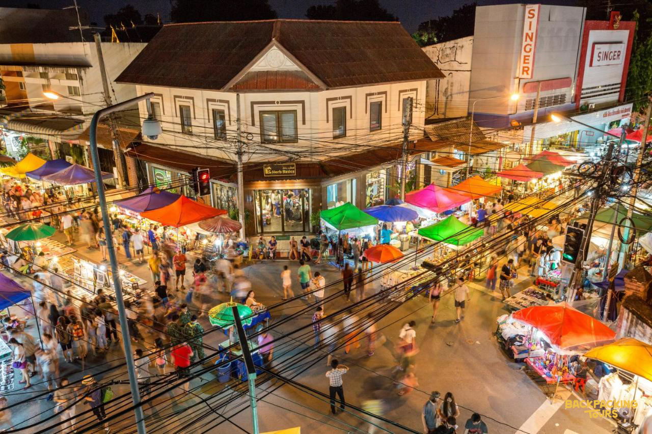 A vibrant night market in Chiang Mai, Thailand, with colorful stalls and many people enjoying the evening.