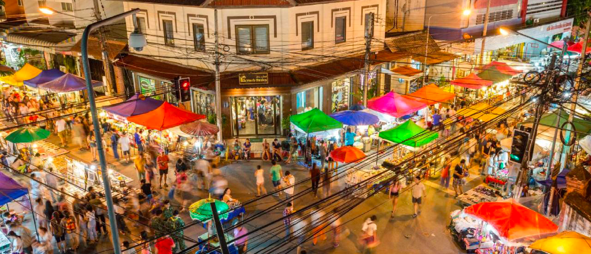 A bustling night market in Chiang Mai with many colorful stalls and people shopping at night.