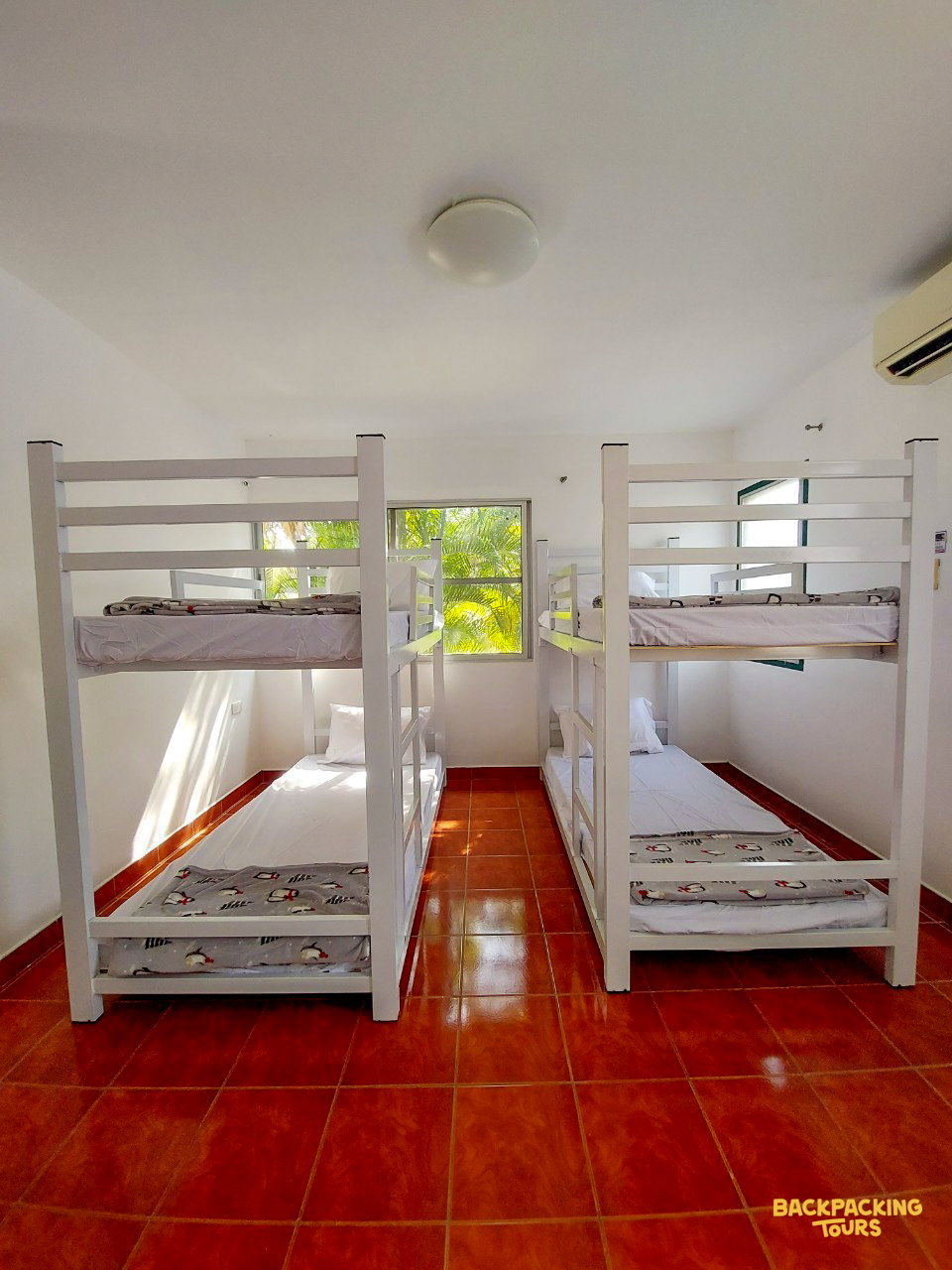 A bright, clean room with two white bunk beds and a tiled floor, ready for volunteers.