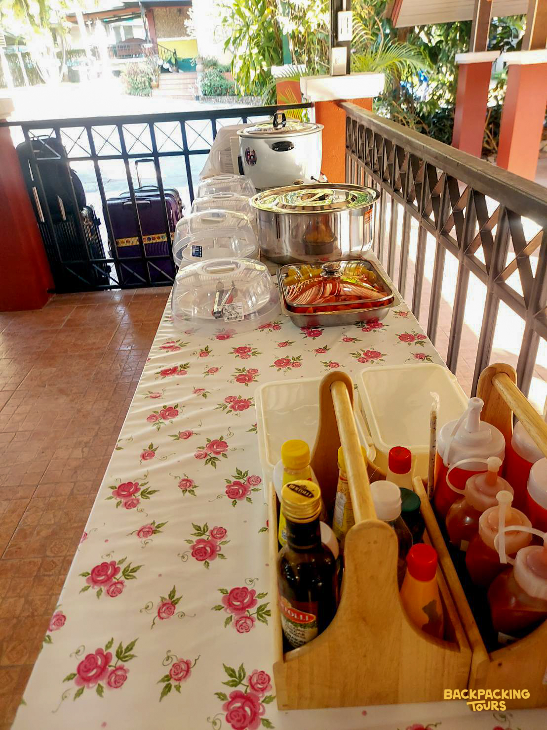 A welcoming outdoor buffet with a variety of food and sauces on a floral table in Thailand.