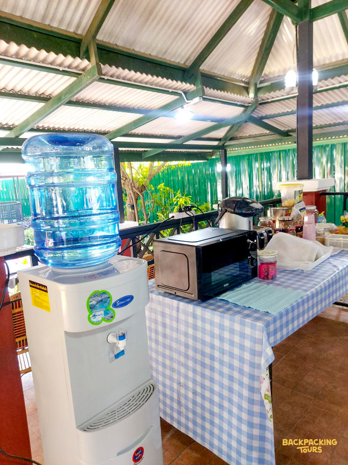 Shared kitchen facilities with a water dispenser and toaster oven in a bright, open-air common area.