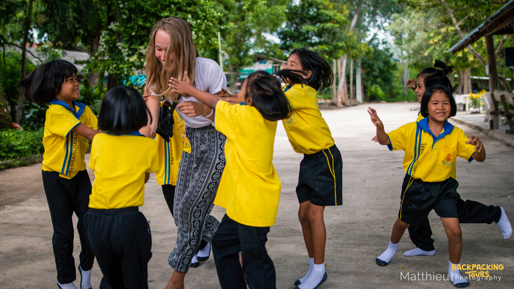 A happy volunteer plays joyfully with smiling Thai kindergarten children in Thailand.