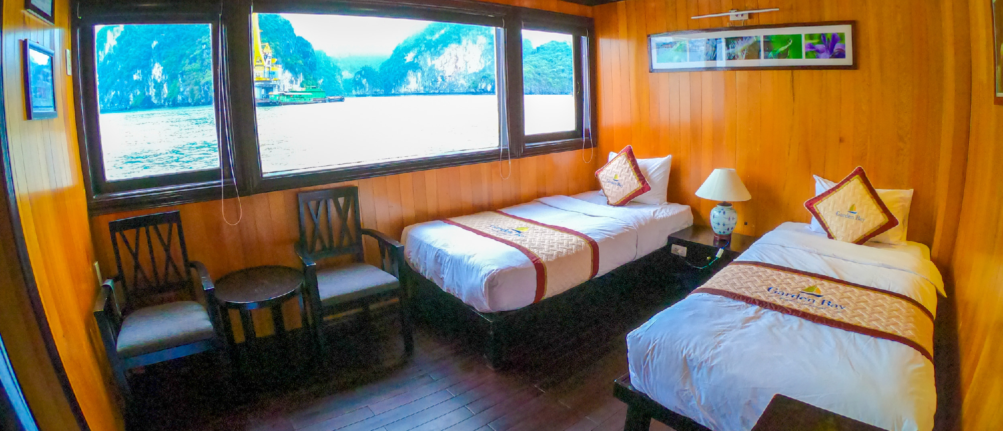 A cozy boat cabin with two single beds and a large window overlooking Halong Bay's karsts.