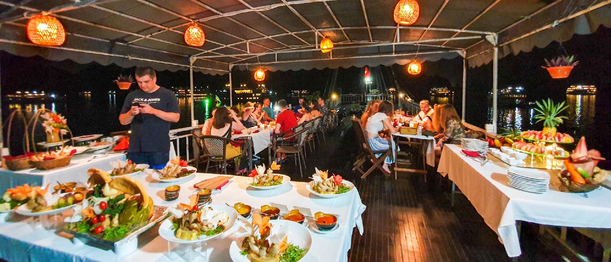 Guests enjoy a vibrant buffet dinner under lanterns on a cruise boat in Halong Bay.