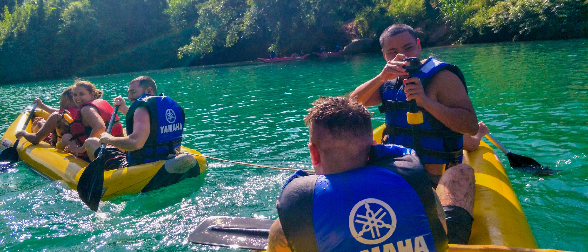 Adventurous tourists in life vests kayak on a beautiful green river in Phong Nha, capturing memories.