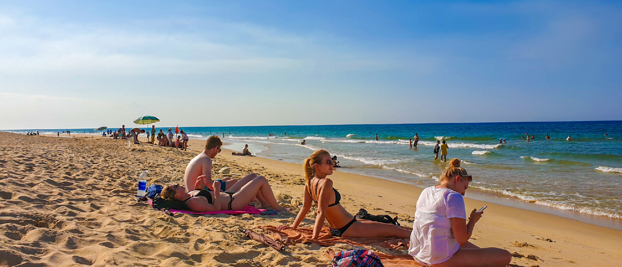 Young people sunbathe and relax on the golden sands of Thuan An Beach in Vietnam.