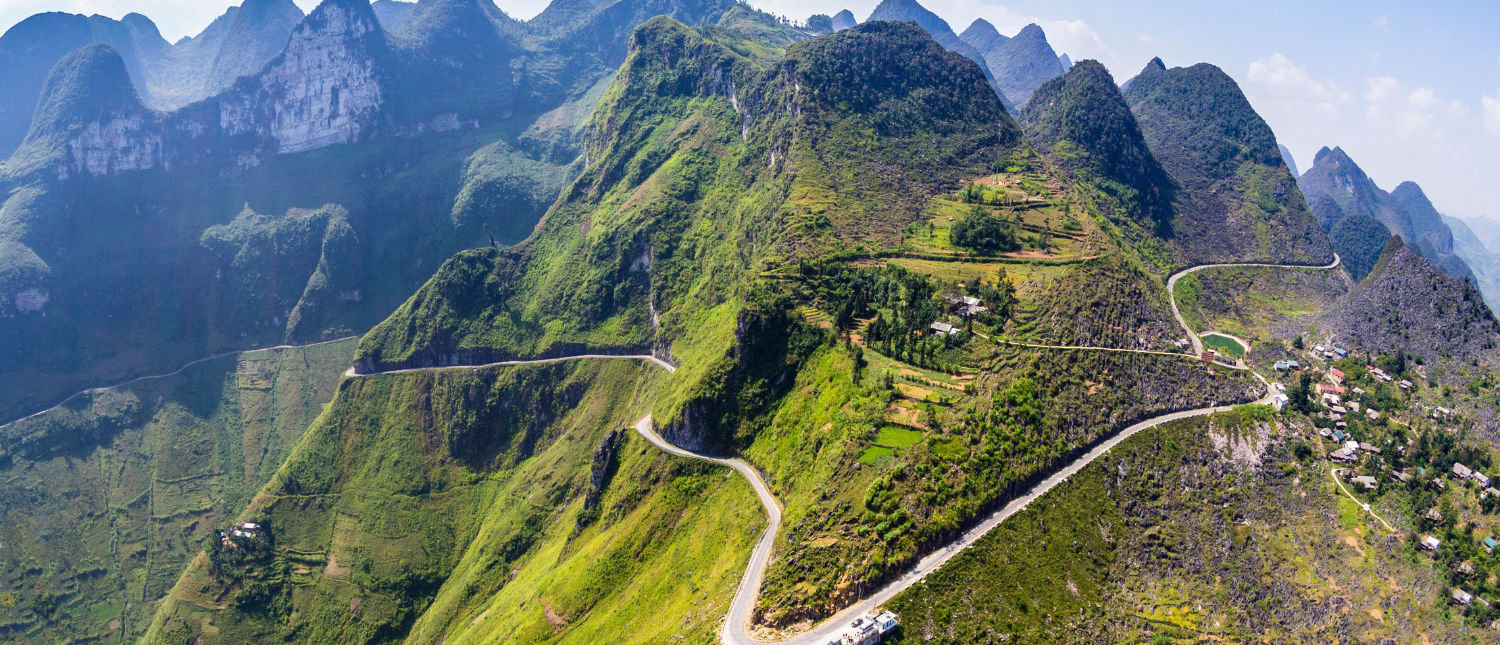 Aerial view of the winding Hai Van Pass road through dramatic green mountains in Vietnam.