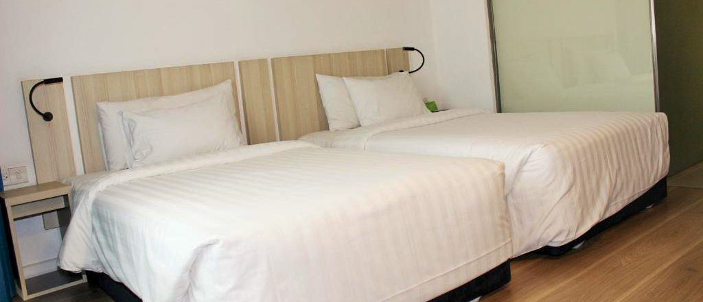 A comfortable, modern hotel room featuring two single beds with crisp white linen.